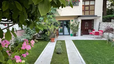 a house with a garden with a table and pink flowers at Visoko New Concept - 7 minutes from the Pyramids - City Center in Visoko