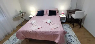 a bedroom with a pink bed with two towels on it at Teslić Apartman NiA in Teslić