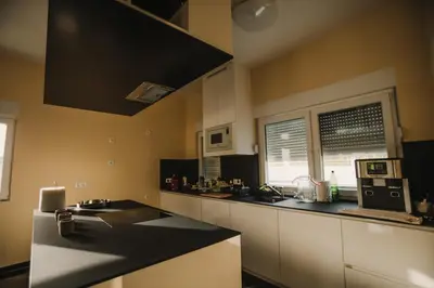 a kitchen with white cabinets and a black counter top at Grand villa Bosnae in Bihać