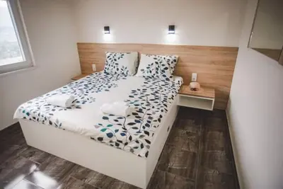 a bedroom with a white bed with a wooden headboard at Villa Vanesa Bihać in Bihać