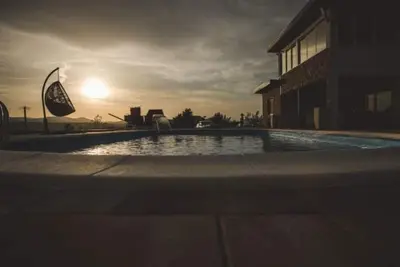 a swimming pool with the sun setting in the background at Villa Vanesa Bihać in Bihać
