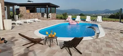 a swimming pool with two chairs and a table and a pool at Villa Vanesa Bihać in Bihać