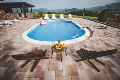 a swimming pool with two chairs and a table and a pink pool at Villa Vanesa Bihać in Bihać