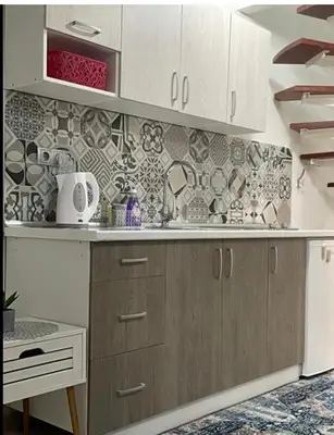 a kitchen with white cabinets and a tile wall at Central13 App 2 in Tuzla