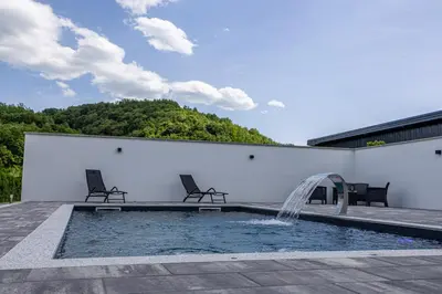 a pool with two chairs and a water fountain at Villa Asja in Bihać