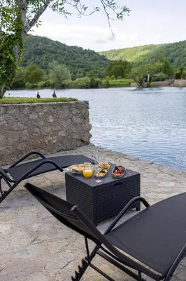 a table and chairs with food on it next to a lake at Villa Asja in Bihać