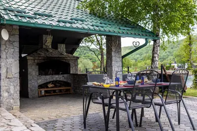 a table and chairs in front of a stone fireplace at Villa Asja in Bihać