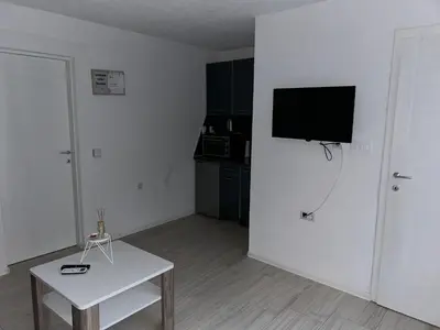a living room with a tv on the wall and a table at Apartman Jasko 2 in Jajce