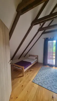 a bedroom with a bed and a blue rug in a attic at Green Garden Lohovo in Bihać