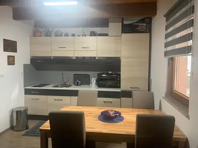 a dining room table with chairs and a kitchen at Green Garden Lohovo in Bihać