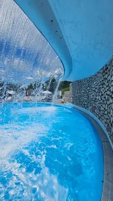 a large pool of blue water with a waterfall at apartman Kami in Tuzla