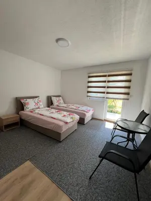 a bedroom with two beds and a table and a chair at Weekend house & apartments Dubrave in Visoko