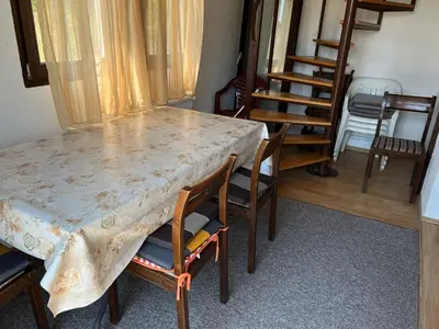 a dining room table with chairs and a table with a curtain at Weekend house & apartments Dubrave in Visoko