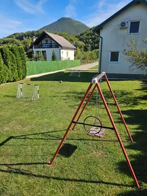 a red swing set in a yard with a house at La Reina Una in Bihać