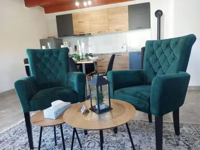 a living room with two green chairs and a table at La Reina Una in Bihać