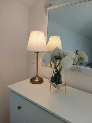 a table with two lamps and a vase of flowers on it at La Reina Una in Bihać