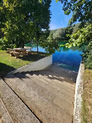 a bench and a picnic table next to a lake at La Reina Una in Bihać