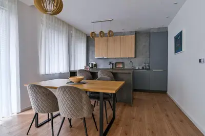 a kitchen and dining room with a wooden table and chairs at Beautiful modern apartment with large livingroom in Bihać