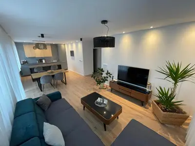 a living room with a blue couch and a table at Beautiful modern apartment with large livingroom in Bihać