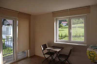 a table and chairs in a room with two windows at Lotus Villas in Travnik