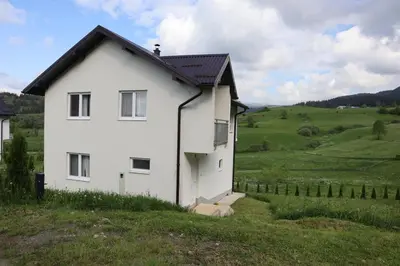 a white house with a black roof in a field at Lotus Villas in Travnik