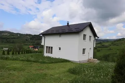 a white house with a black roof on a green field at Lotus Villas in Travnik