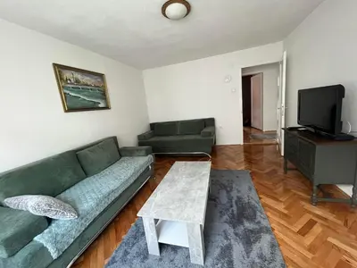 a living room with a green couch and a tv at Apartment Bedem Center in Bihać