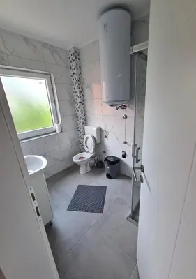 a bathroom with a toilet and a sink and a window at Apartmani Bugojno in Bugojno