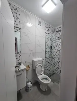 a white bathroom with a toilet and a sink at Apartmani Bugojno in Bugojno