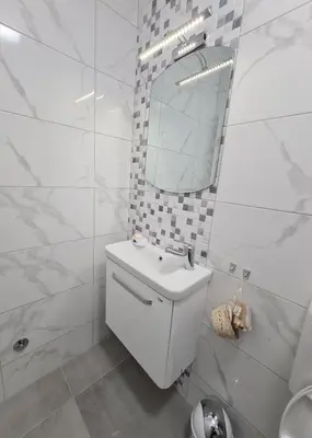 a white bathroom with a sink and a mirror at Apartmani Bugojno in Bugojno