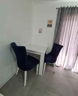 a white desk with two blue chairs next to a window at Apartmani Bugojno in Bugojno