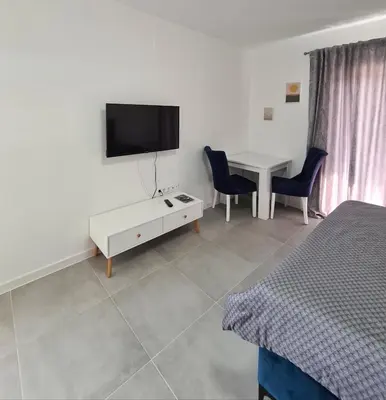 a room with a table and a tv and a bed at Apartmani Bugojno in Bugojno