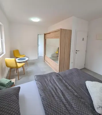 a bedroom with a bed and a table and a chair at Apartmani Bugojno in Bugojno