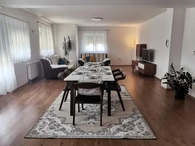 a dining room and living room with a table and chairs at Apartman Sali in Bihać