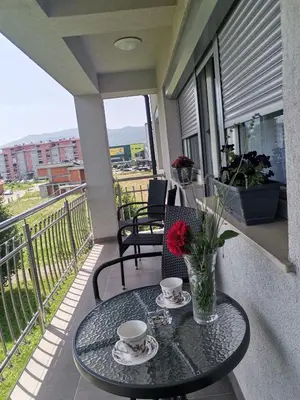 a table with two cups and a vase with flowers on a balcony at Apartman Sali in Bihać
