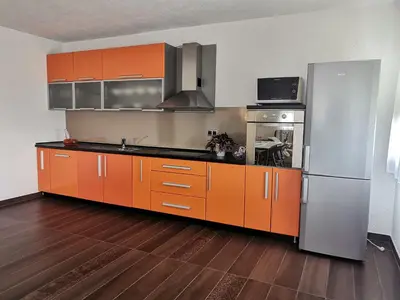 a kitchen with orange cabinets and a stainless steel refrigerator at Apartman Sali in Bihać
