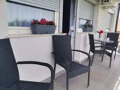 a patio with chairs and a window with flowers on it at Apartman Sali in Bihać