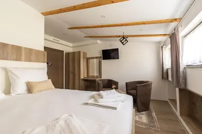 a bedroom with a large white bed and chairs at Verdi Rooms in Visoko