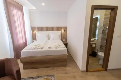 a small bedroom with a bed and a bathroom at Verdi Rooms in Visoko