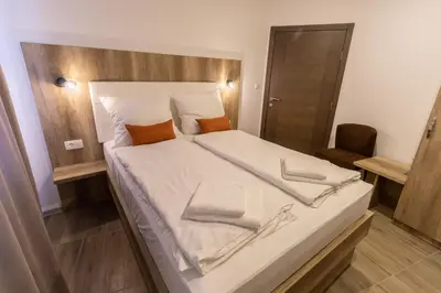 a large bed with white sheets and orange pillows at Verdi Rooms in Visoko
