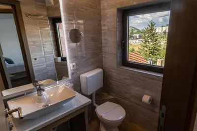 a bathroom with a sink and a toilet and a window at Verdi Rooms in Visoko