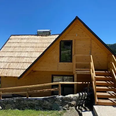 a log cabin with a staircase in front of it at Prokoško jezero Zlatna koliba in Fojnica