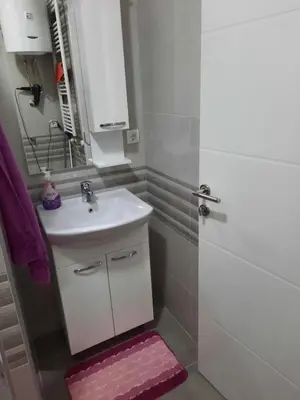 a bathroom with a sink and a shower with a mirror at Apartman Bulevar in Doboj