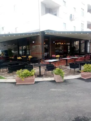 a building with tables and chairs in front of it at Apartman Gavric in Doboj