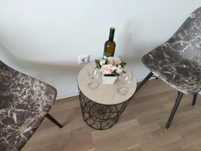 a table with a bottle of wine and flowers on it at Apartmani Sarah 2 Tuzla in Tuzla