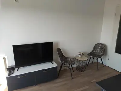 a living room with two chairs and a flat screen tv at Apartmani Sarah 2 Tuzla in Tuzla