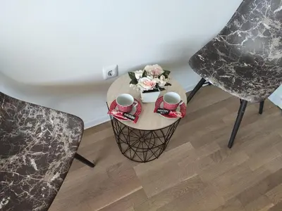 a table with a bowl of flowers and two chairs at Apartmani Sarah 2 Tuzla in Tuzla