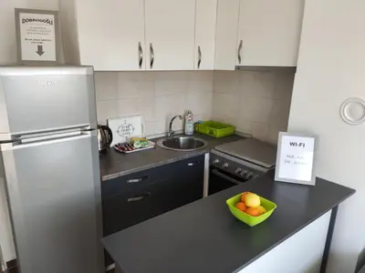 a kitchen with a refrigerator and a bowl of fruit on a counter at Apartmani Sarah 2 Tuzla in Tuzla