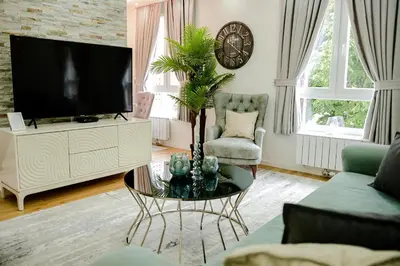 a living room with a tv and a table with a plant at Fontana apartmani FREE parking in Tuzla