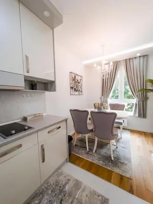 a kitchen with white cabinets and a table with chairs at Fontana apartmani FREE parking in Tuzla